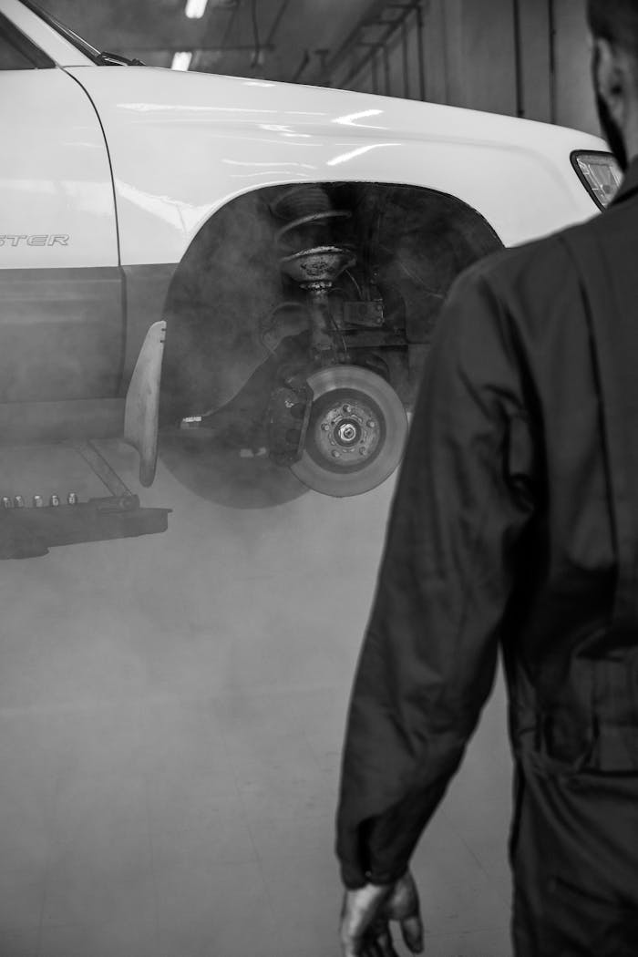 Mechanic approaches a lifted car in a workshop for inspection and maintenance.
